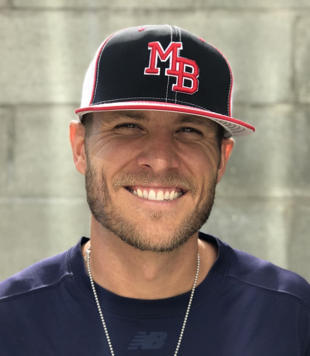 Coach Isaac Hess smiling in a black MADE Baseball cap